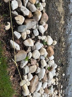 A pile of rocks is sitting on the ground next to a grassy area.