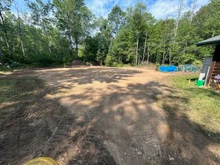 A dirt road leading to a house in the woods.