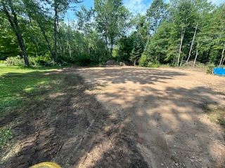 A dirt road in the middle of a forest surrounded by trees.