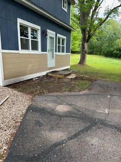 A blue house with a driveway and a tree in front of it.