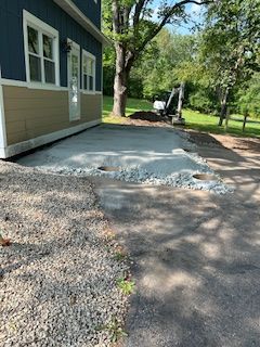 A blue house with a gravel driveway in front of it.