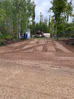 A dirt road leading to a house in the woods.
