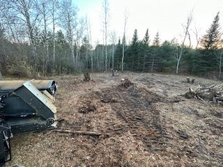 A tractor is sitting in a field with trees in the background.