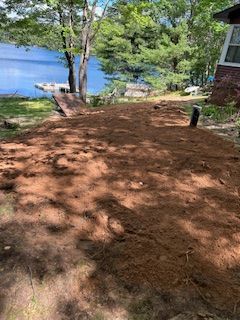 A dirt road leading to a house next to a lake.