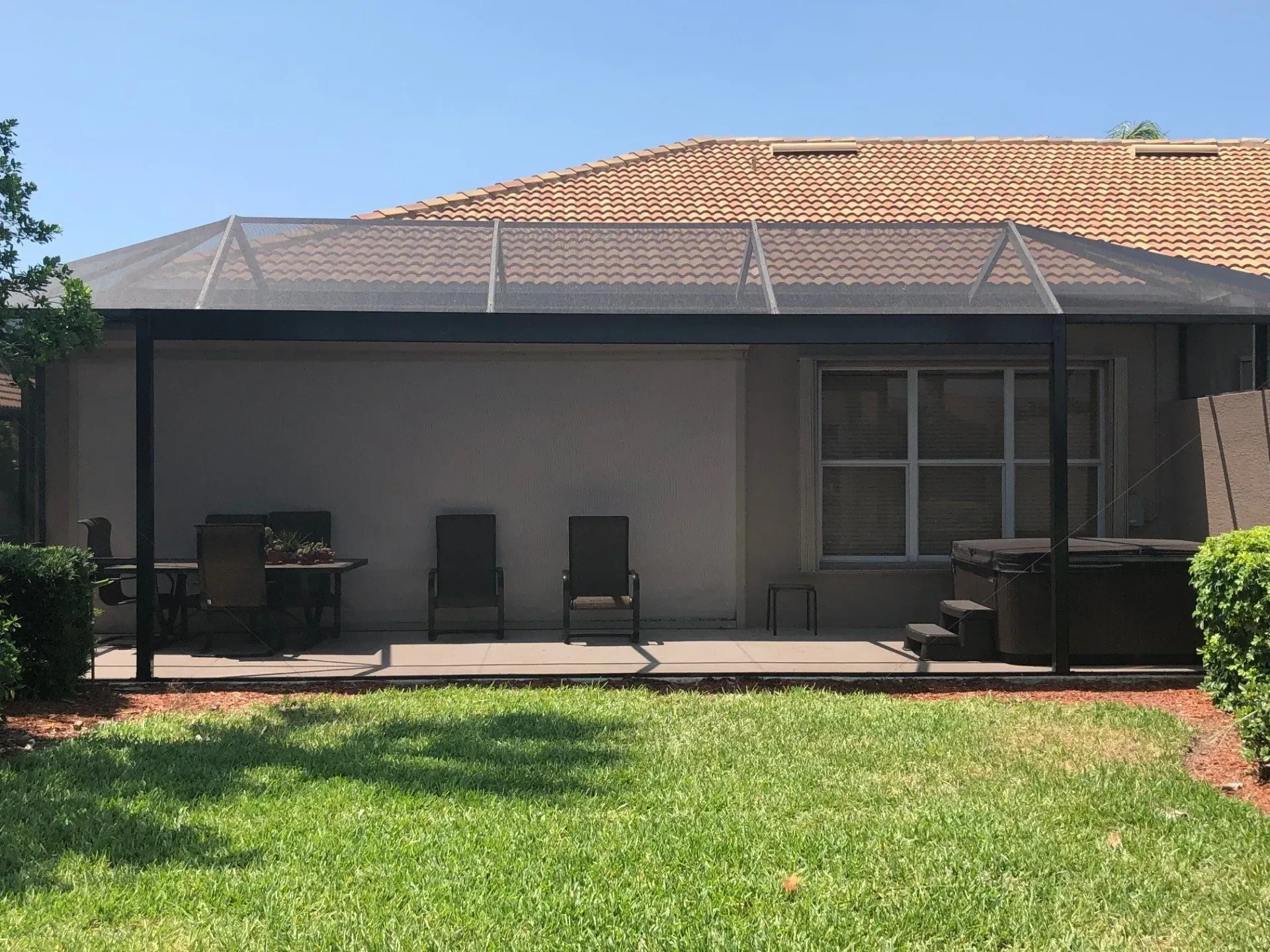 A patio with a canopy and chairs in front of a house.