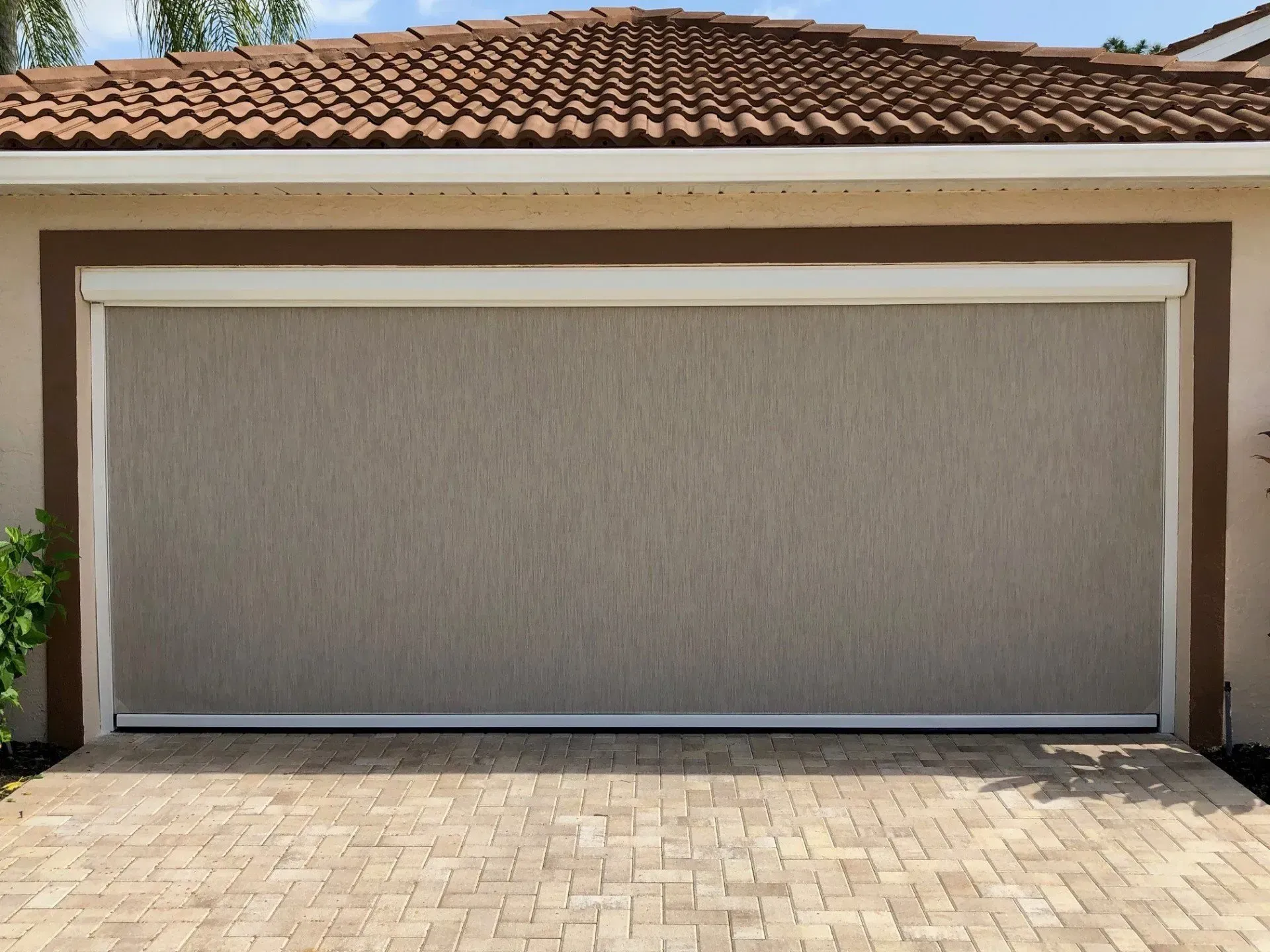 A garage door with a screen on it and a brick driveway