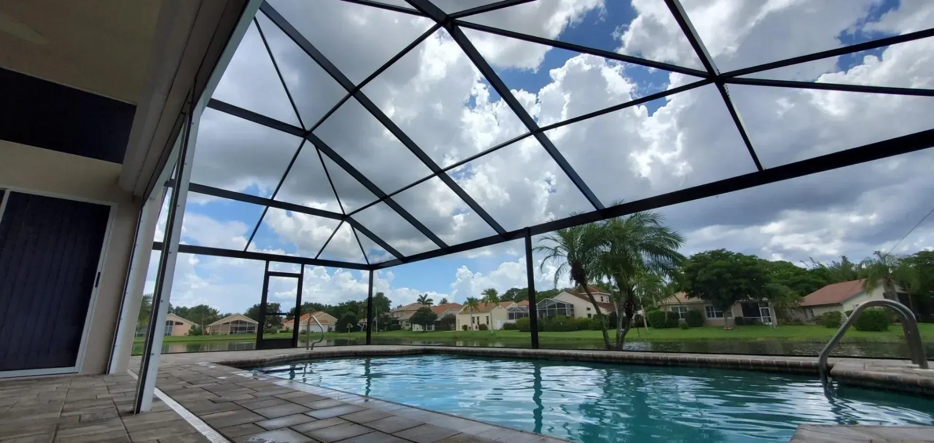 A large swimming pool is covered by a screened in area.