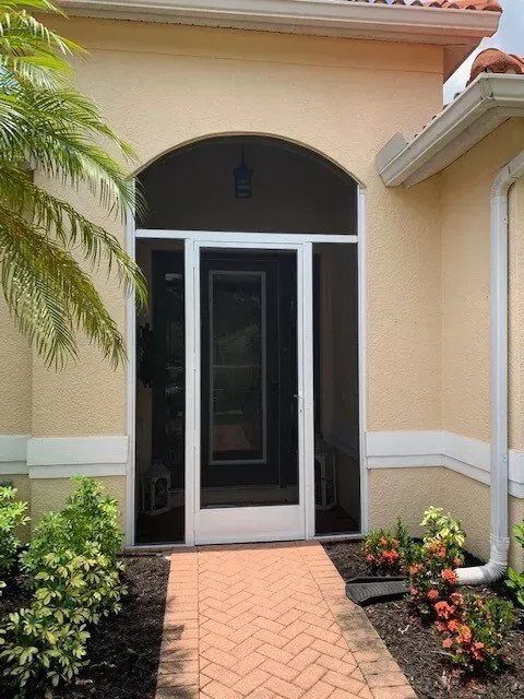 A house with a screened in porch and a brick walkway