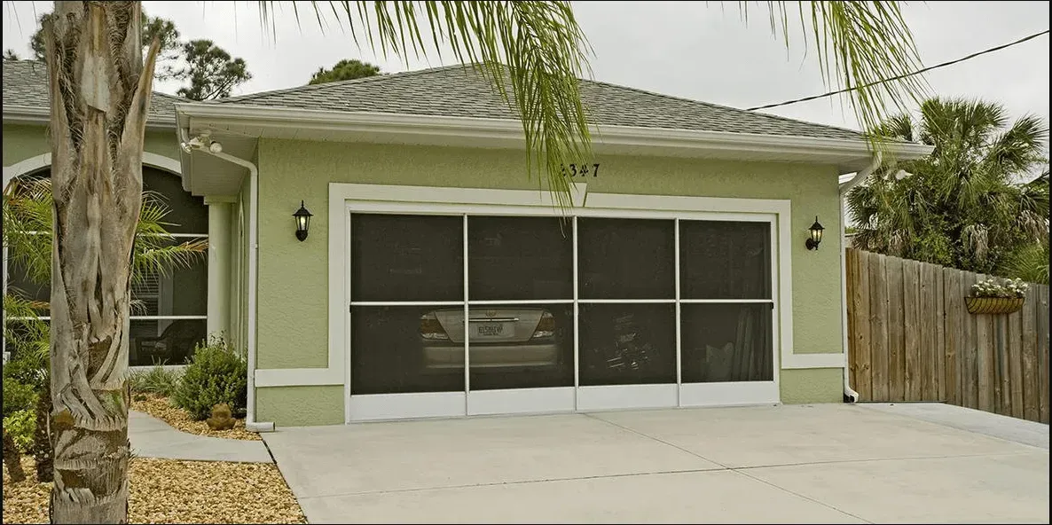 A green house with a screened in garage door.