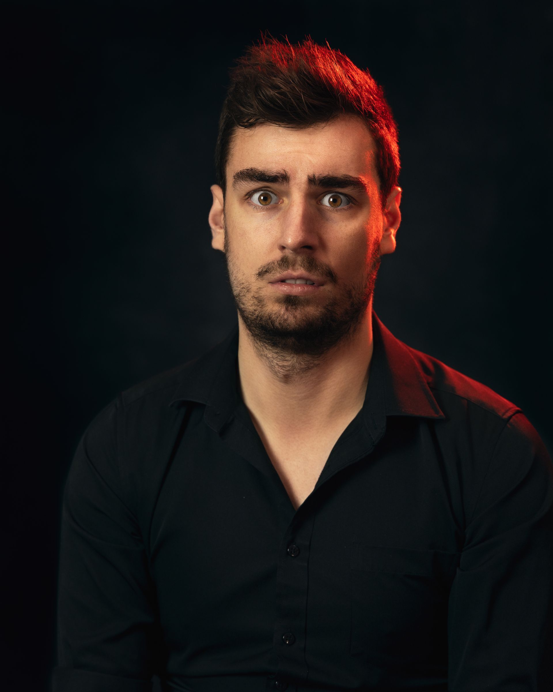 a man with a beard is wearing a black shirt and looking at the camera .