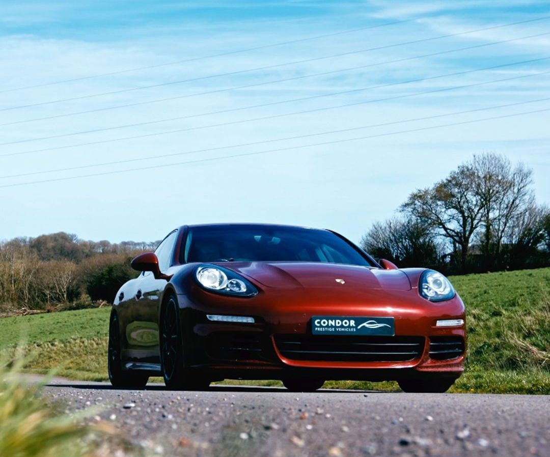 A red sports car is driving down a country road.
