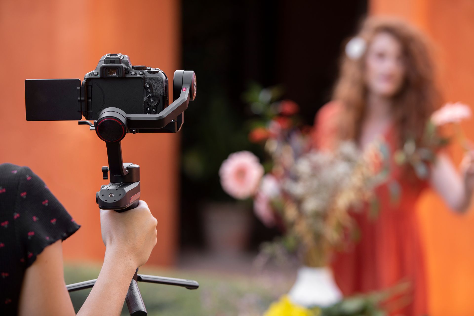 A woman is holding a bouquet of flowers in front of a camera.