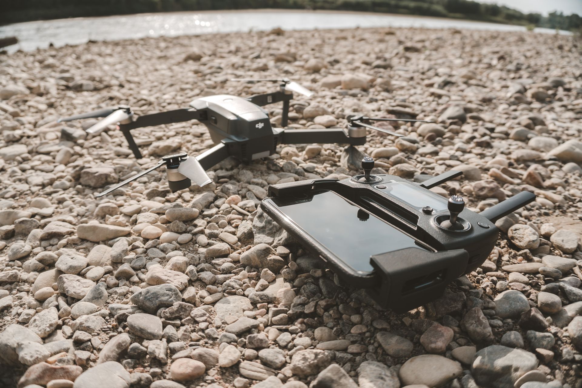 A drone and remote control are sitting on a rocky beach in Devon.