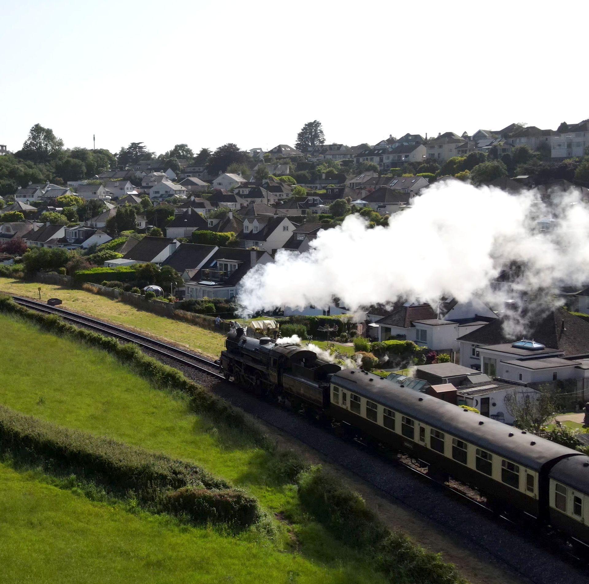 a steam train in paignton is going down the tracks with smoke coming out of it