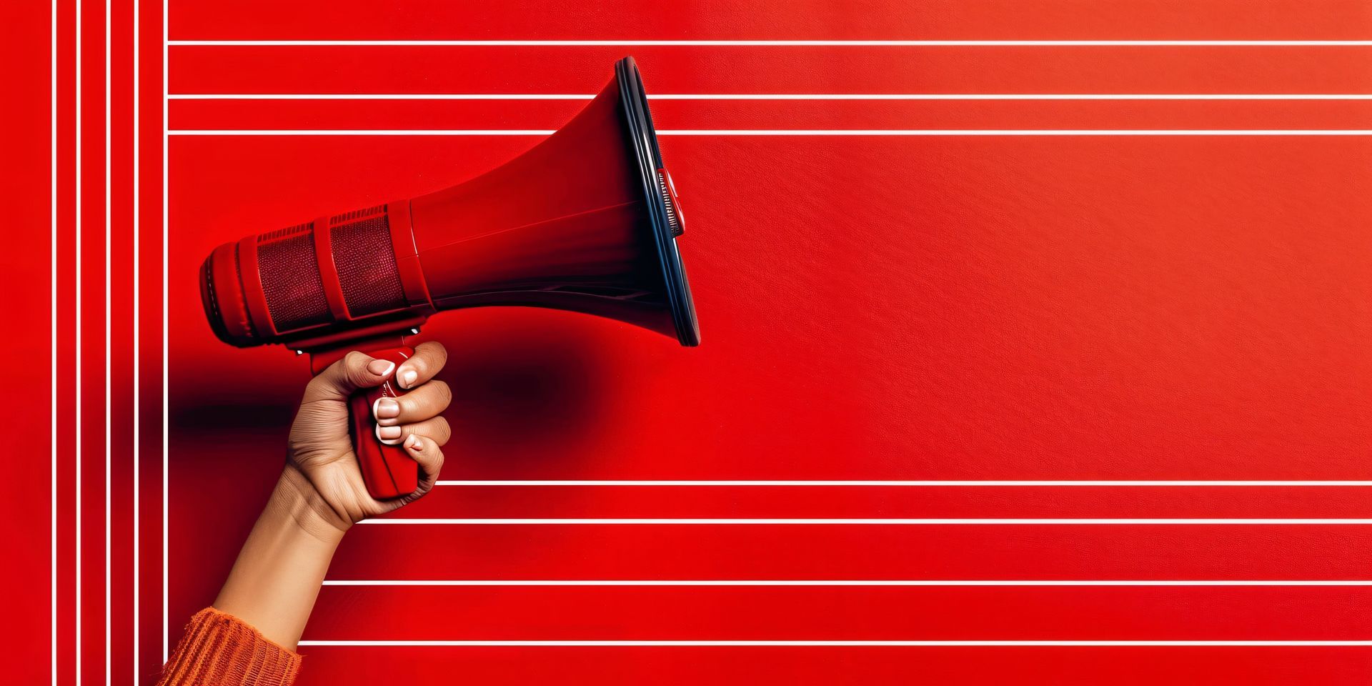 A person is holding a red megaphone in front of a red wall.