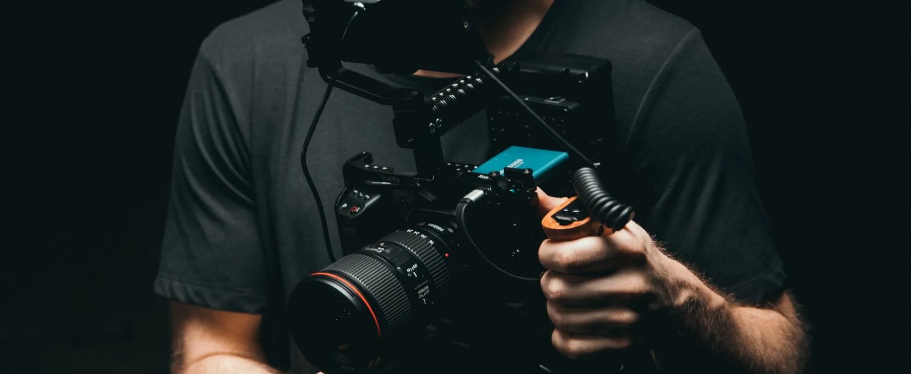 a man is holding a camera in his hands in a dark room.