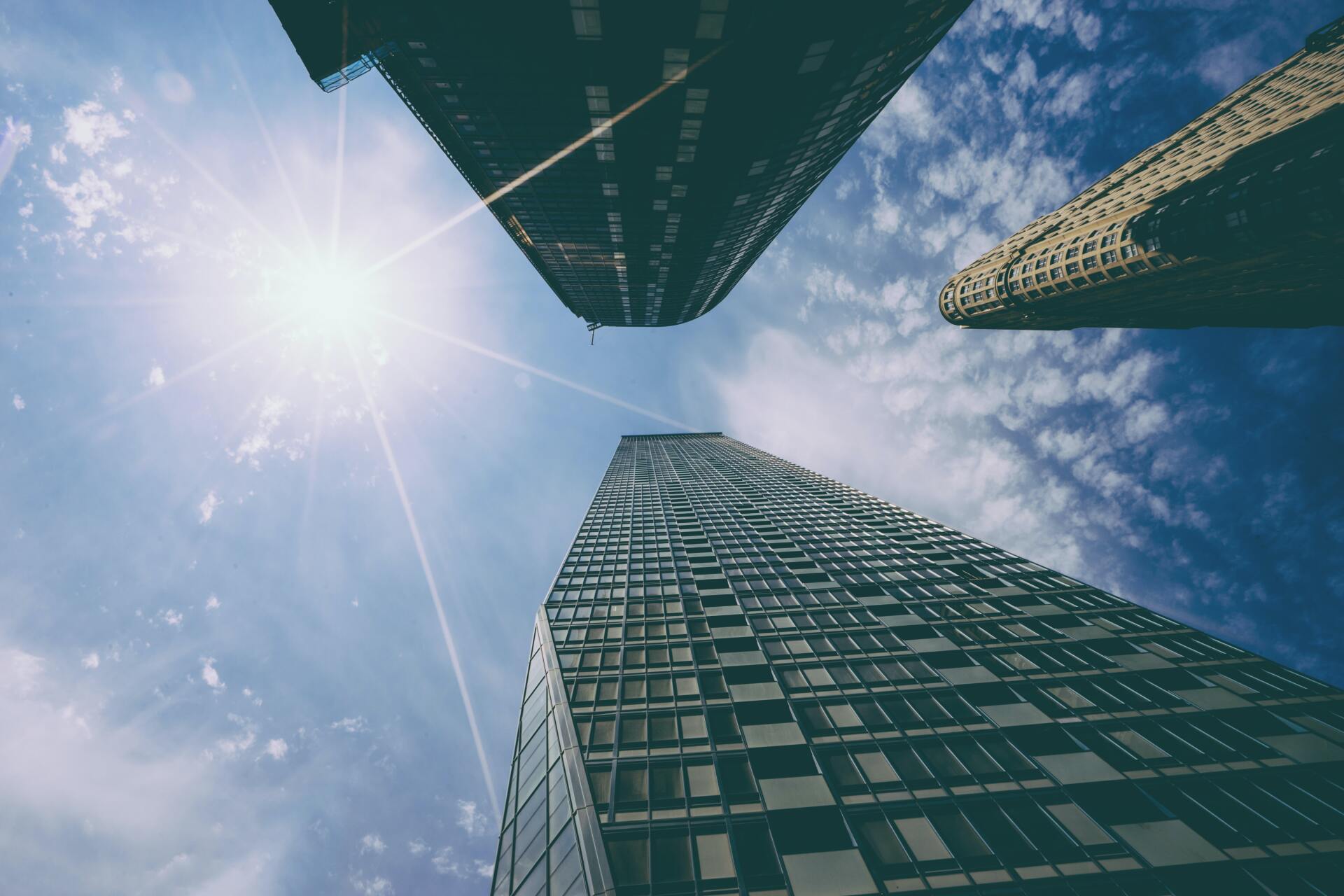 looking up at a tall building with the sun shining through the windows .