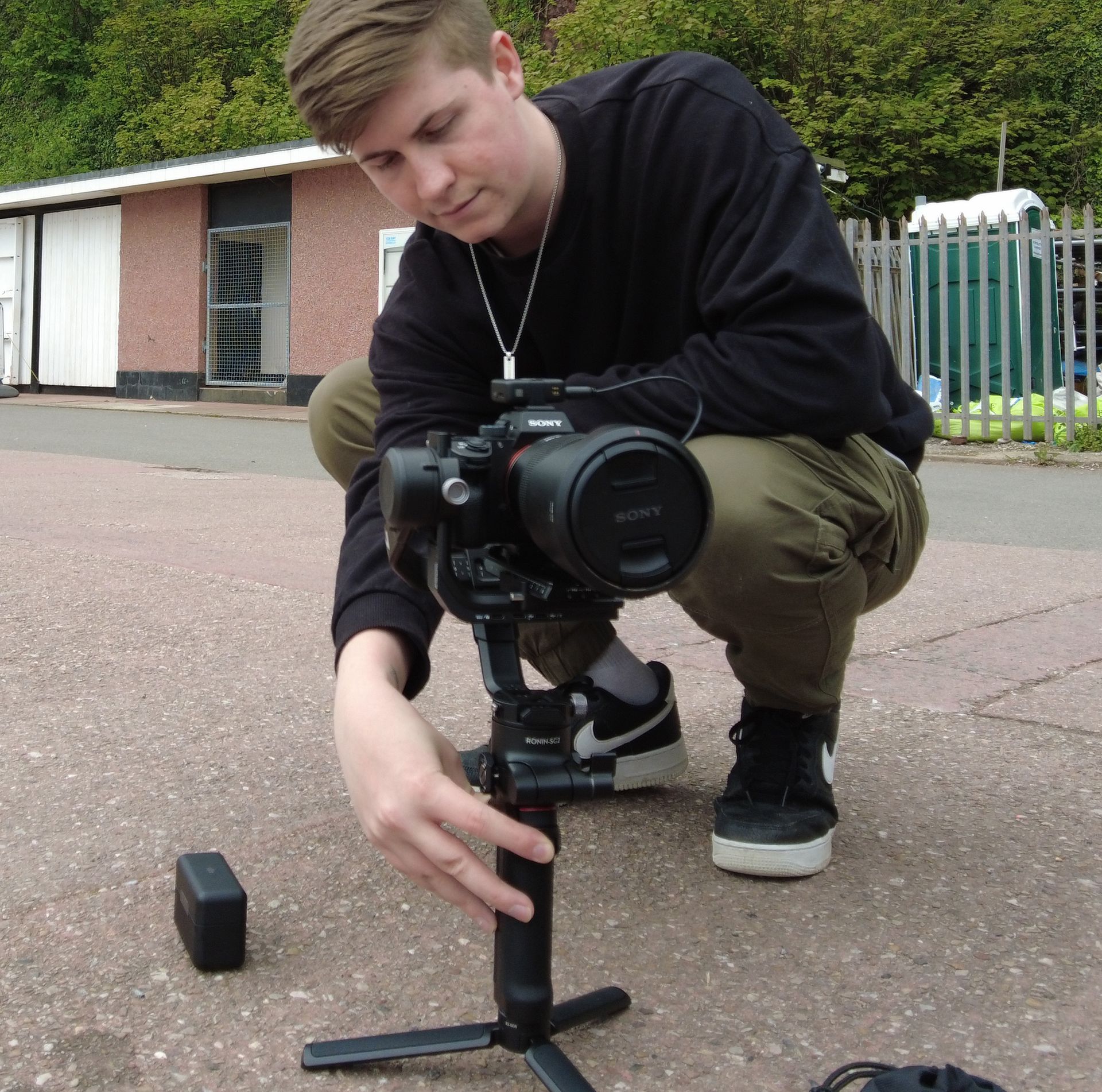 A man kneeling down with a sony camera on a tripod filming content for a business