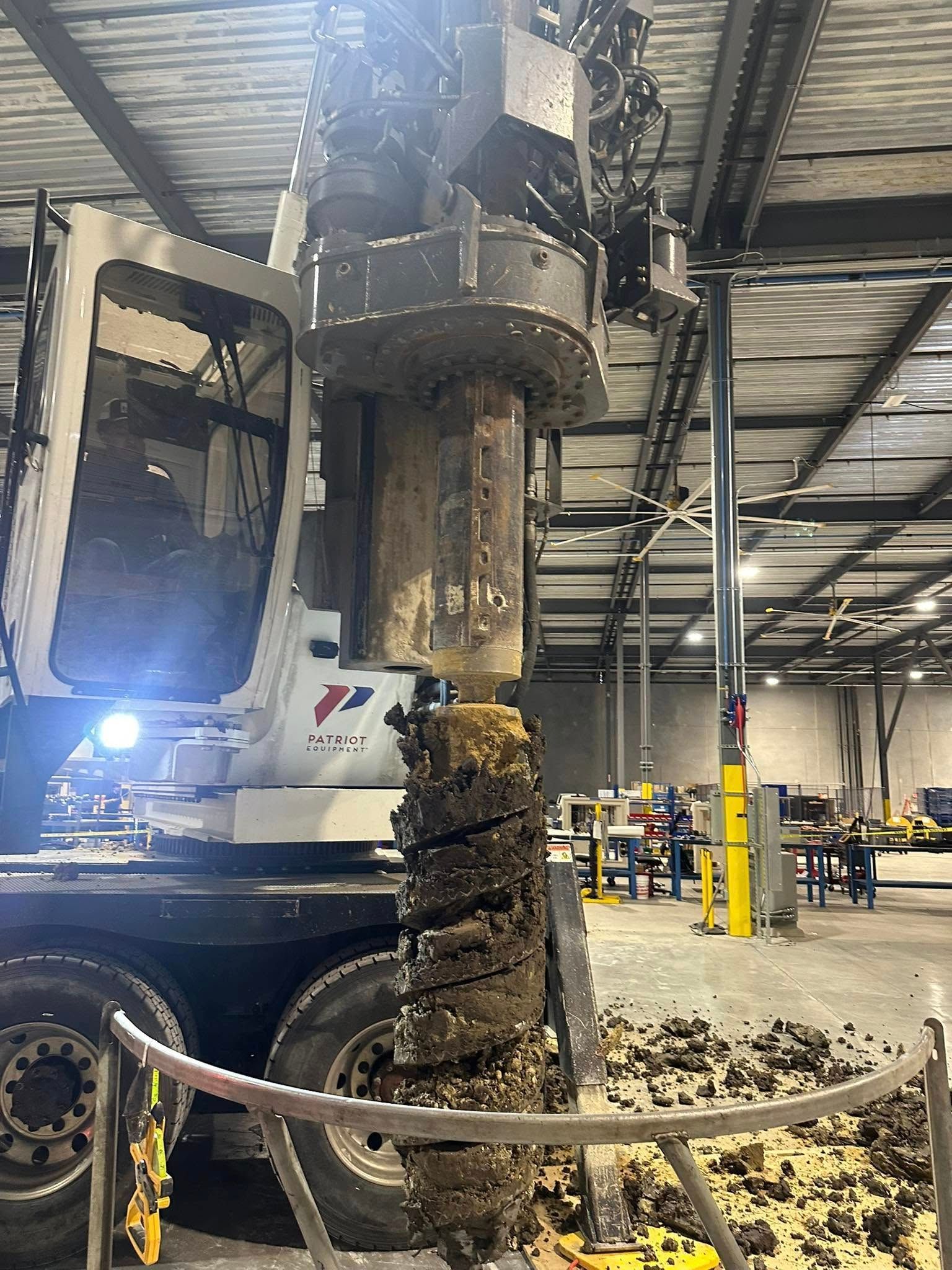 A machine is drilling a hole in the ground in a warehouse.