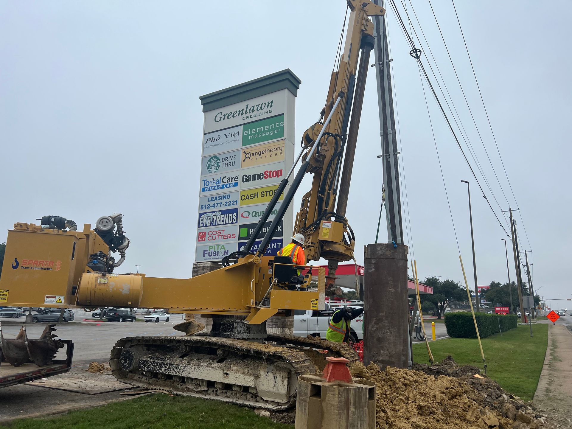A large excavator is working on a construction site next to a sign.