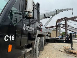 A truck with a crane attached to it is parked on a construction site.