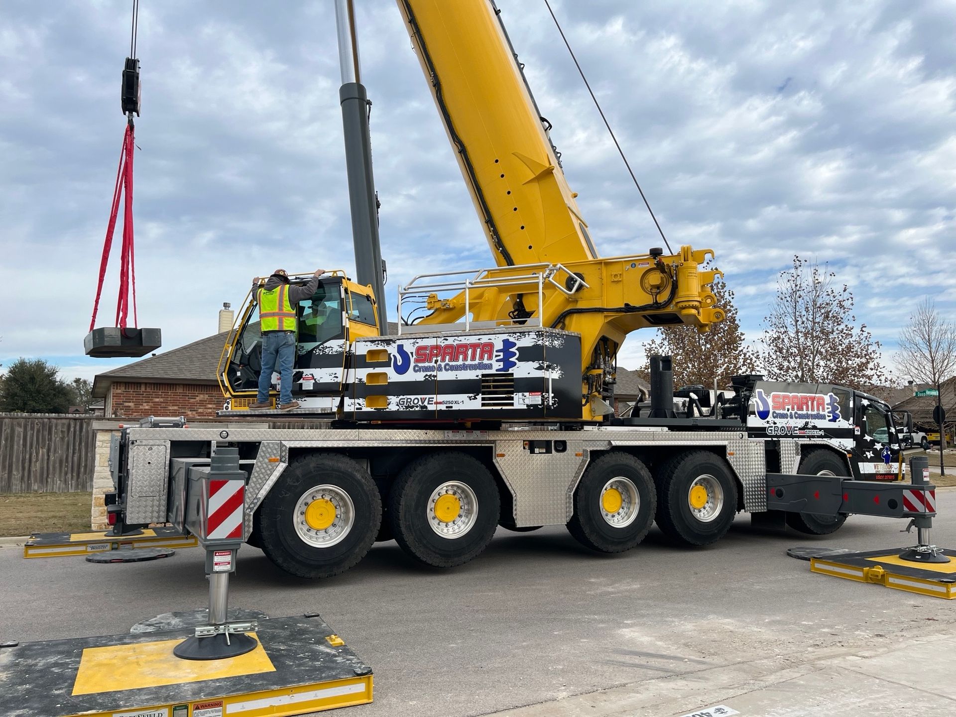 A large yellow crane is parked on the side of the road.