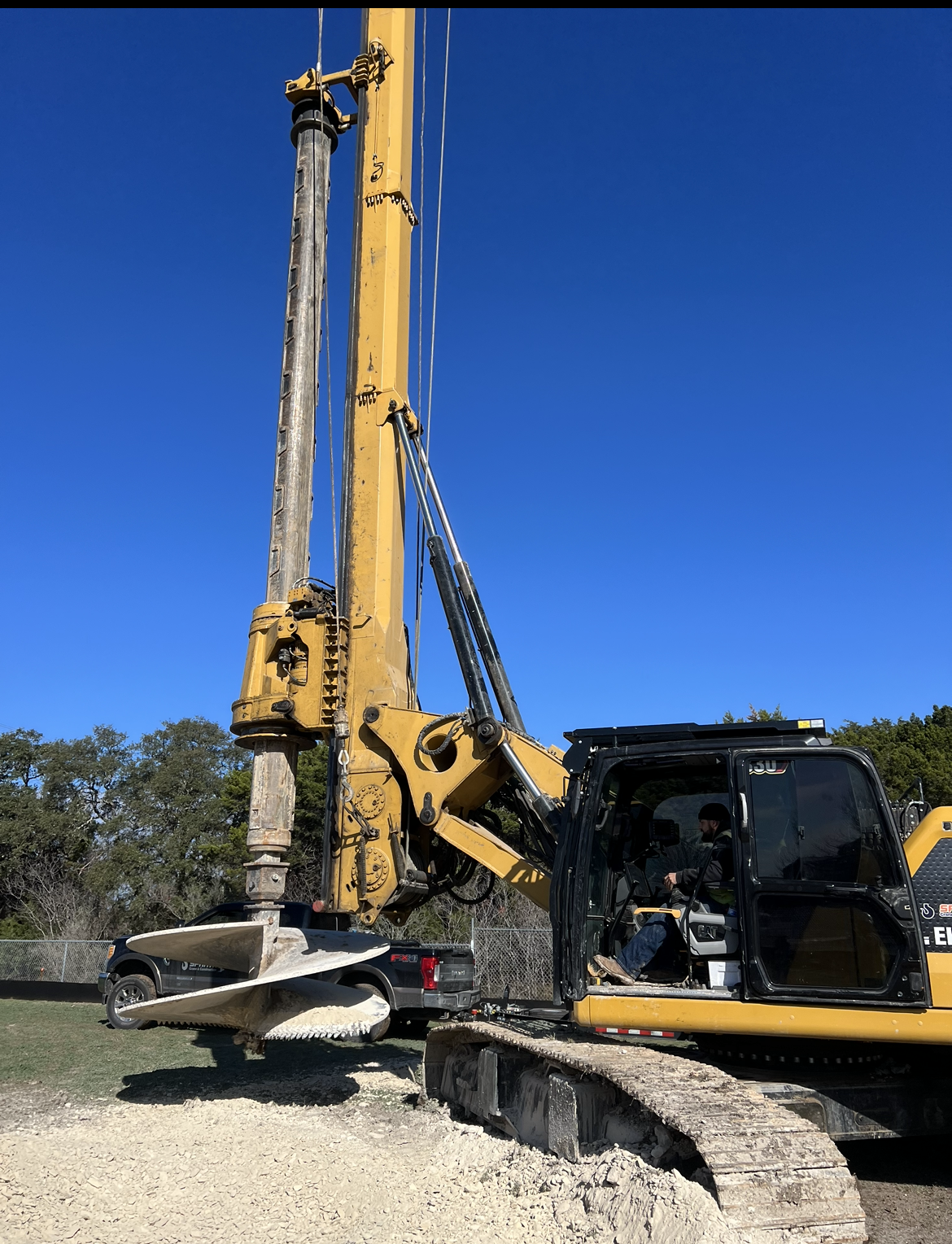 A large yellow excavator is sitting on top of a pile of gravel.
