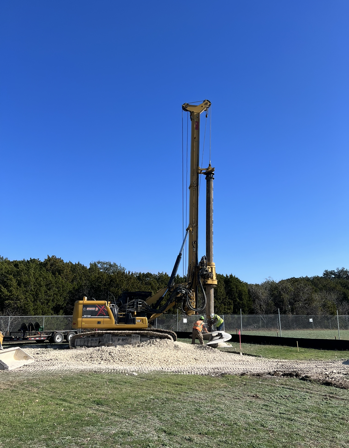A large yellow excavator is sitting in the middle of a grassy field.