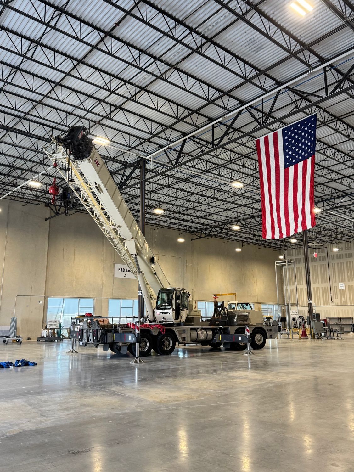 A large warehouse with a crane and an american flag hanging from the ceiling.
