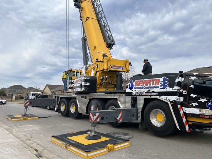 A large crane is sitting on top of a truck in a parking lot.