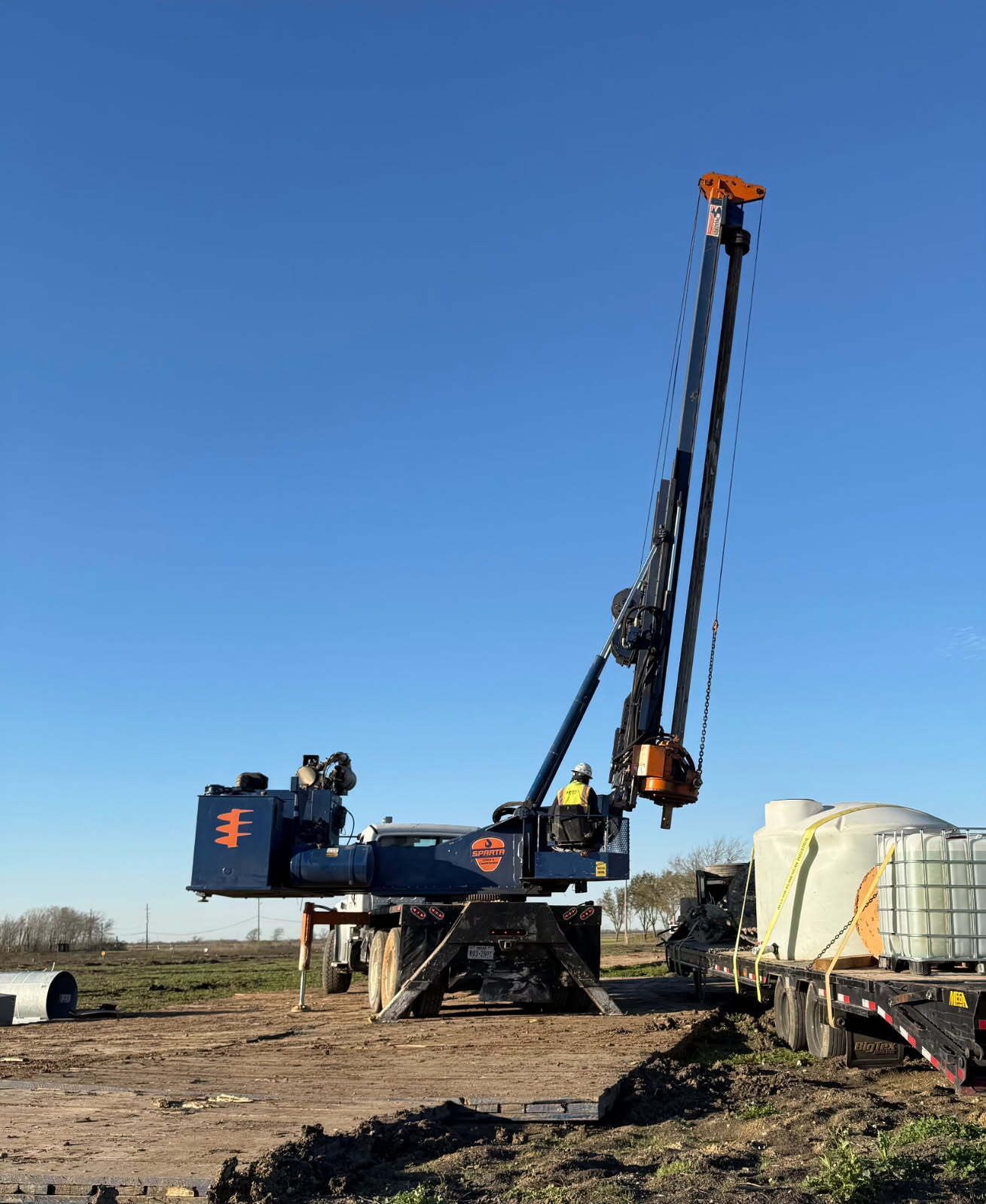 A large crane is sitting in the middle of a dirt field.