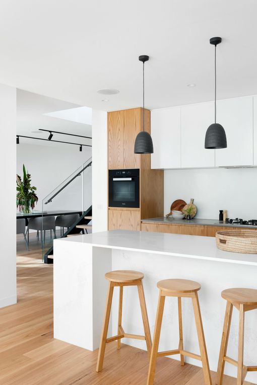 A kitchen with white cabinets and wooden stools.