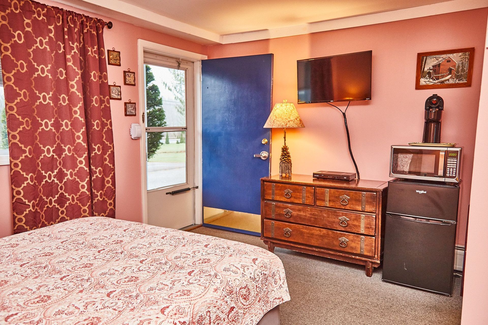 a bedroom with a bed , dresser , television and microwave .