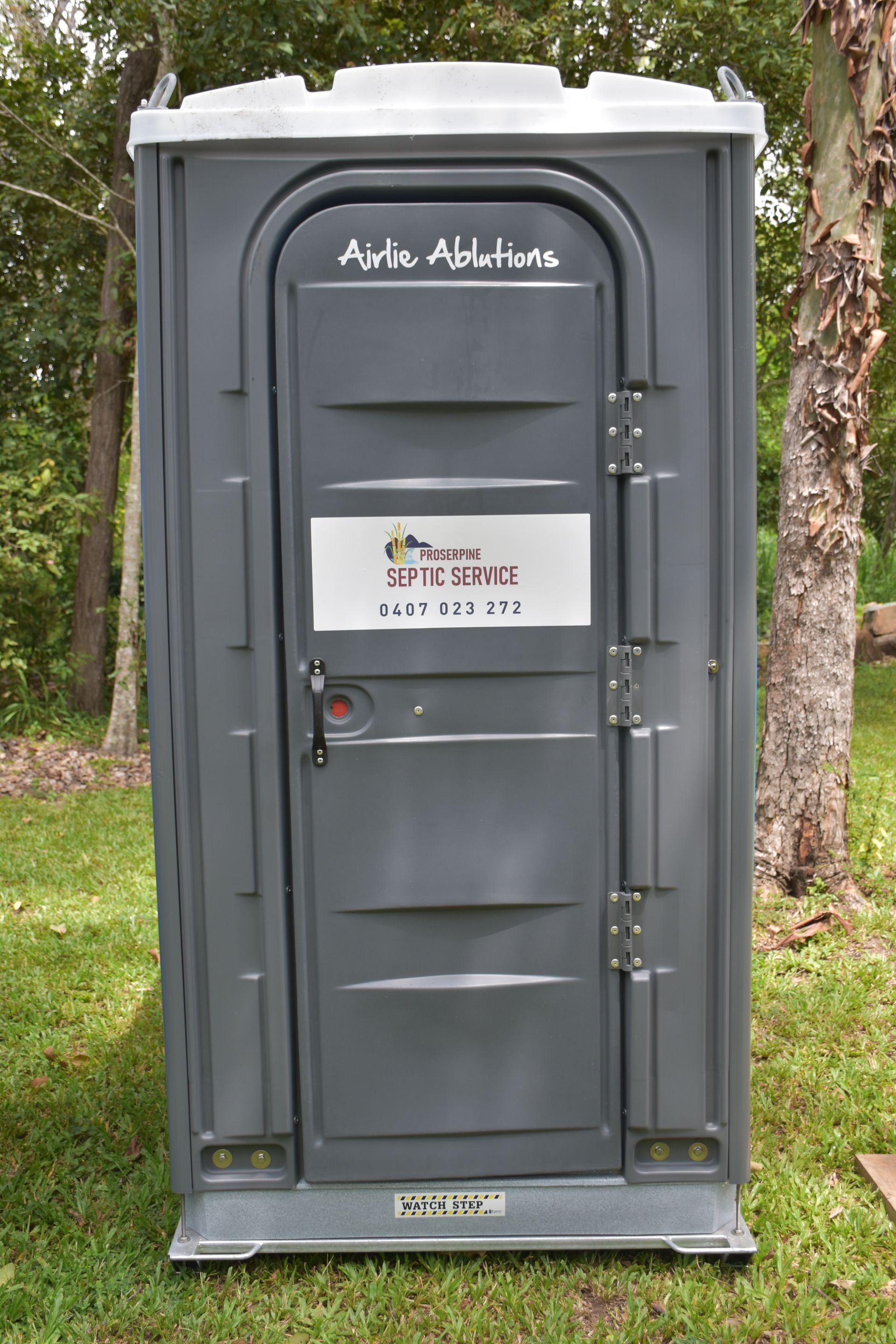 A Portable Toilet is Sitting on Top of a Lush Green Field — Proserpine Septic Service In Cannonvale, QLD
