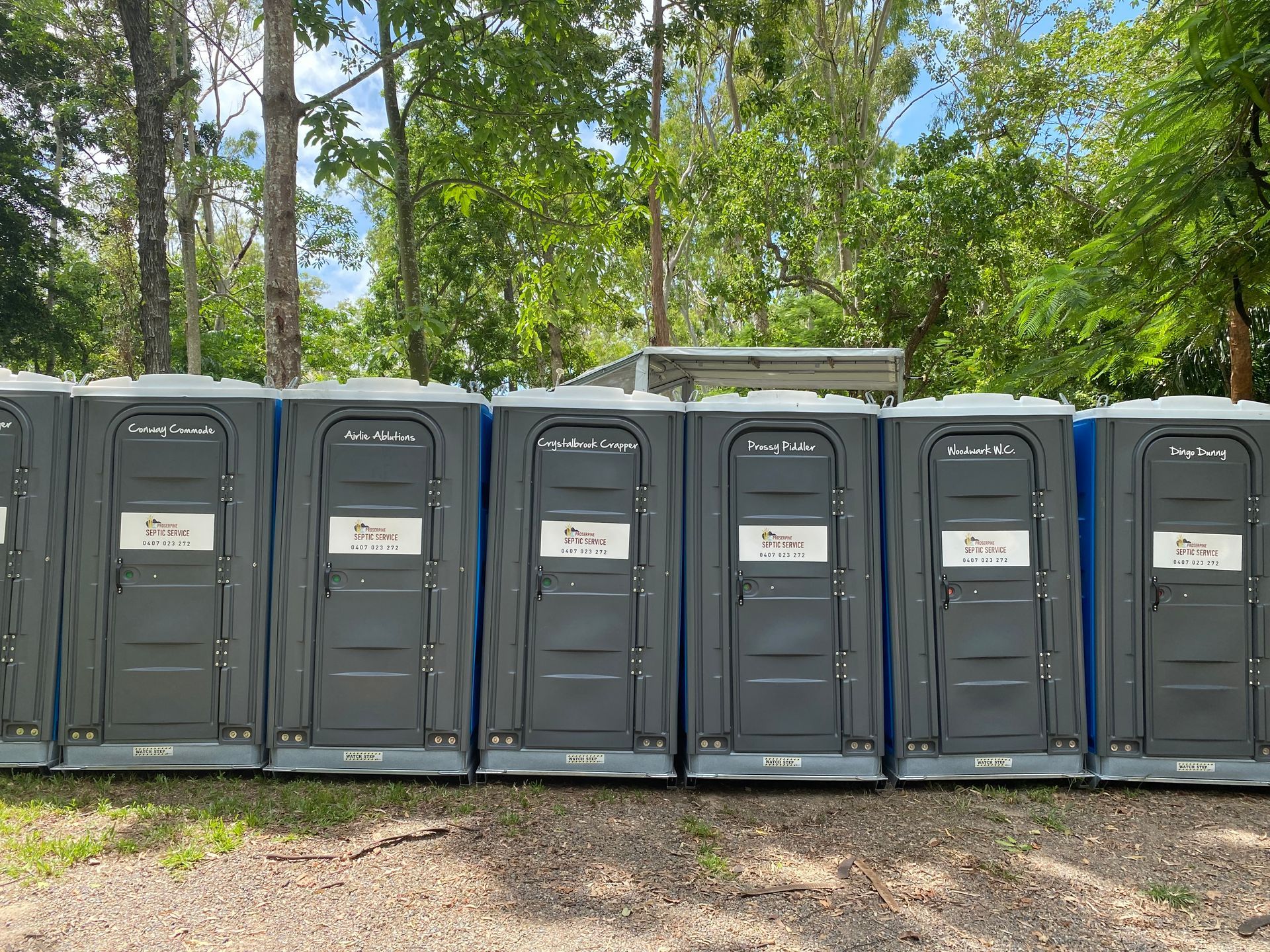A Row of Portable Toilets Are Lined Up in a Field — Proserpine Septic Service In Cannonvale, QLD