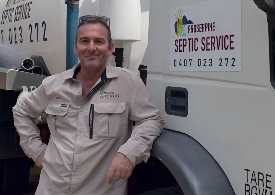 A Man is Sitting in Front of a Septic Service Truck — Proserpine Septic Service In Cannonvale, QLD