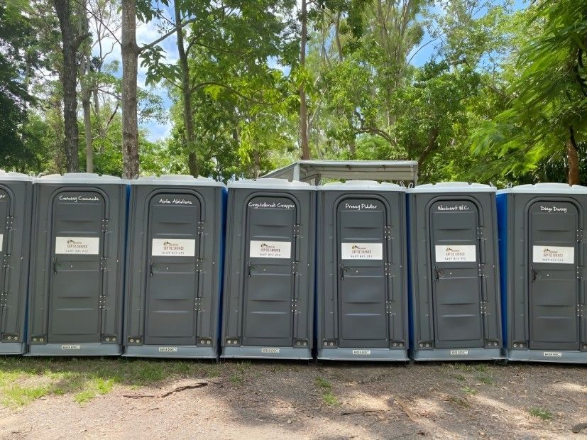 A Row of Portable Toilets Are Lined Up in a Field — Proserpine Septic Service In Airlie Beach, QLD