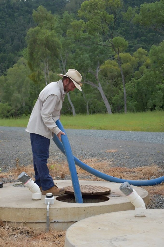A Man in a Cowboy Hat is Clearing Waste Into a Septic Tank — Proserpine Septic Service In Airlie Beach, QLD