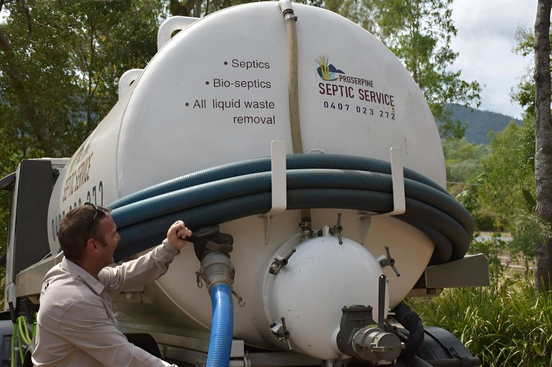 A Man is Sitting on the Back of a Septic Tank — Proserpine Septic Service In Cannonvale, QLD