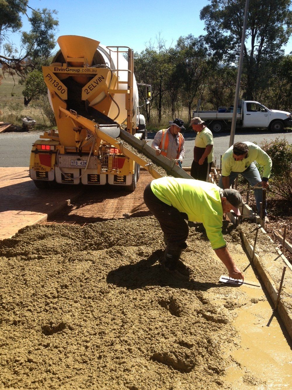 A group of construction workers are working on a concrete driveway