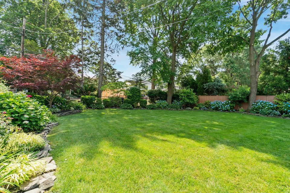 A large lush green lawn with trees and bushes in the background.