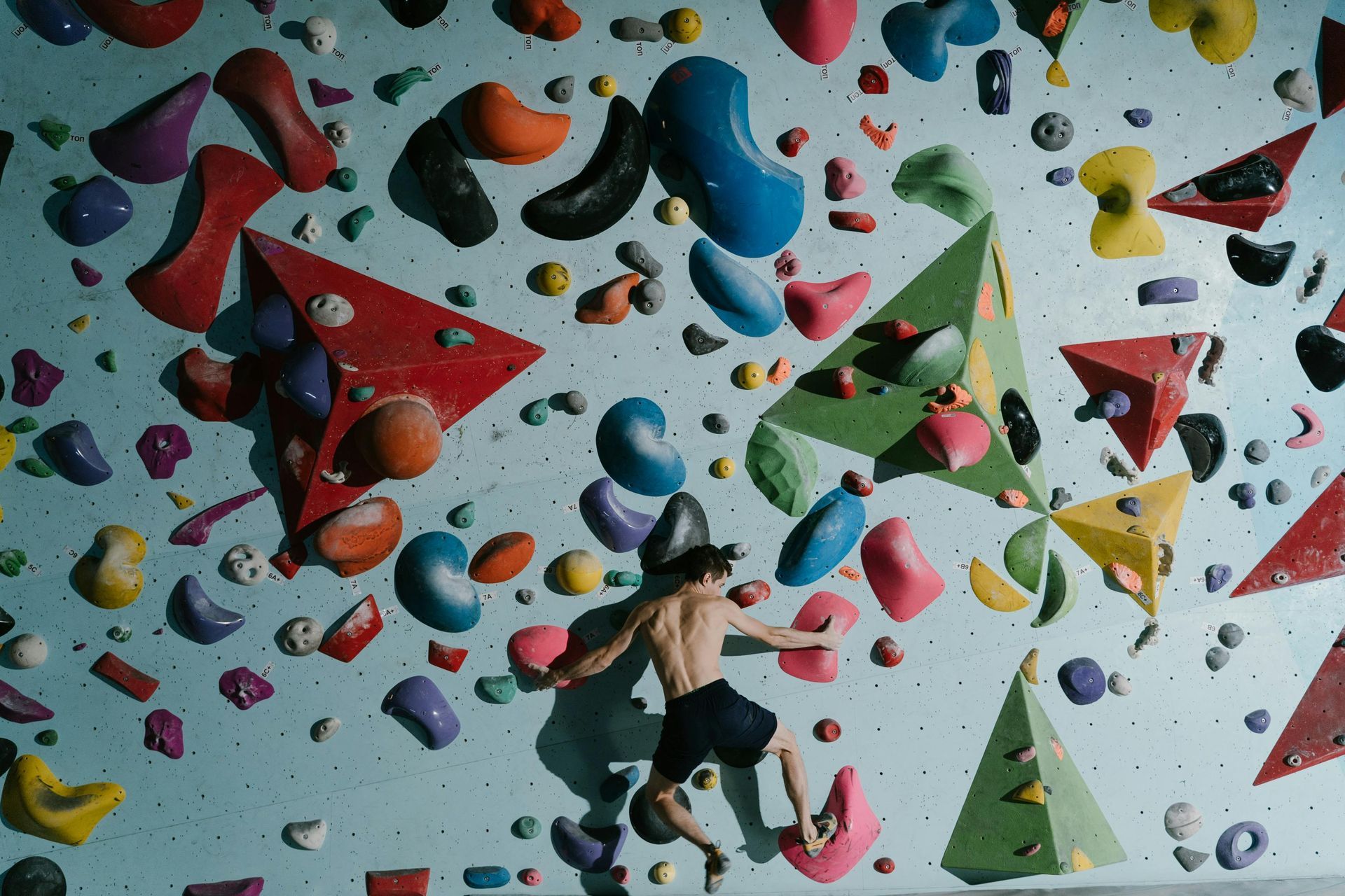 A man is climbing a climbing wall with lots of rocks.