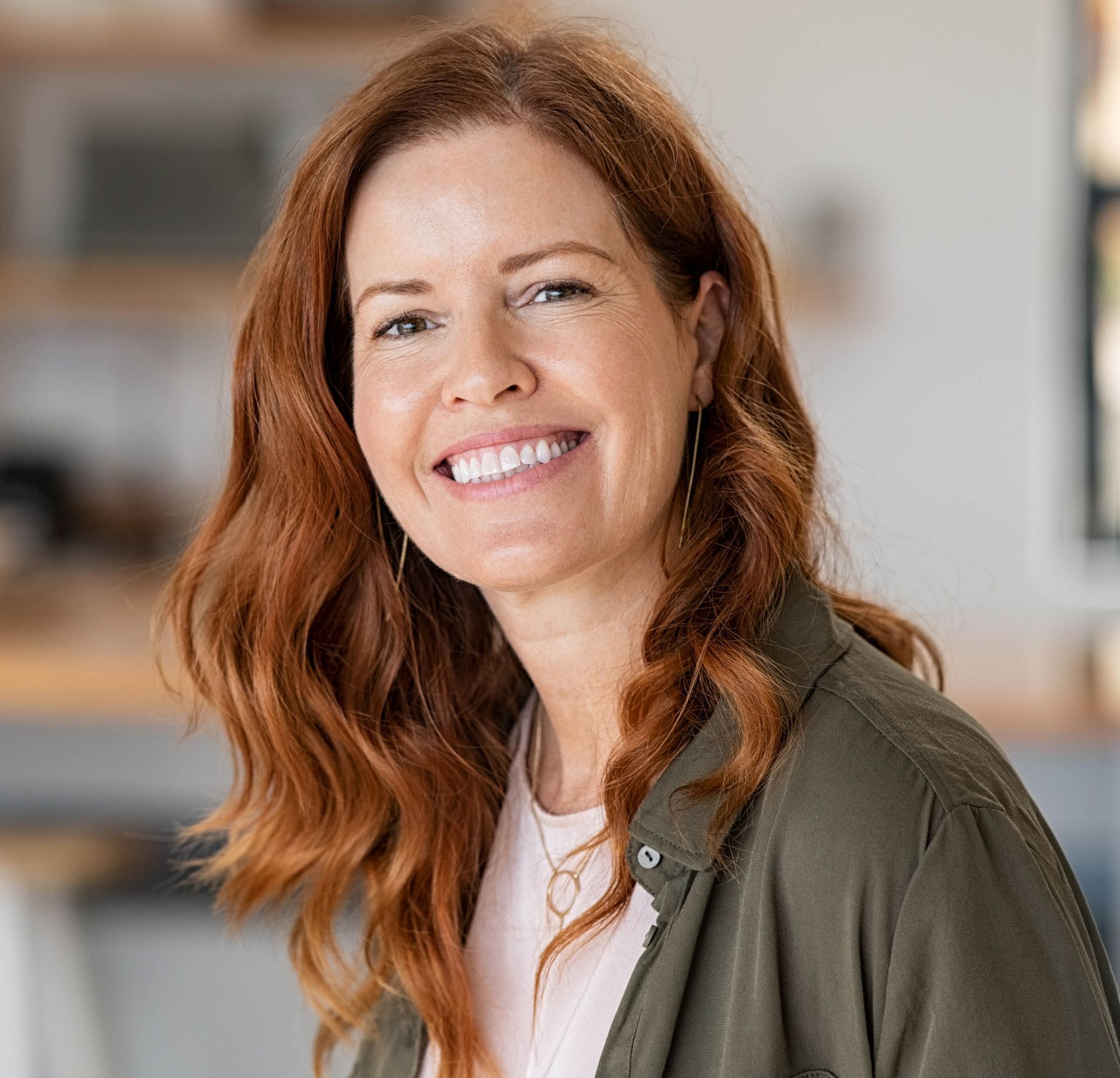 A woman with red hair is smiling for the camera.