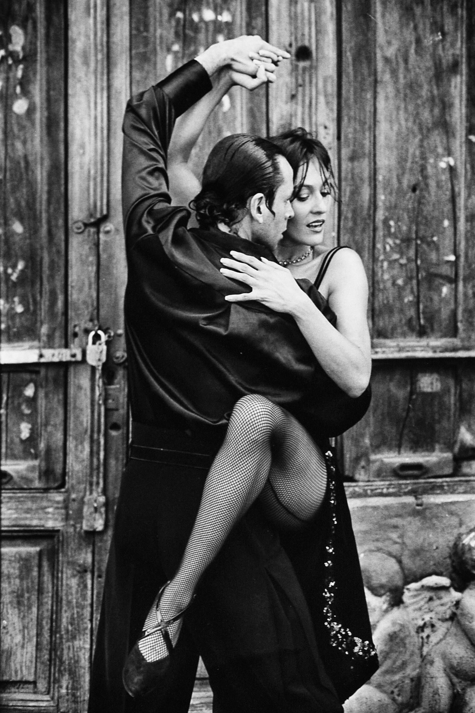 A man is holding a woman in his arms while dancing tango.
