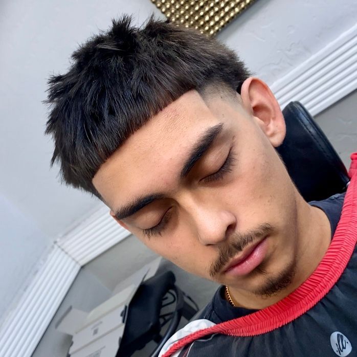 Man with a textured haircut and a neat mustache, eyes closed, resting.