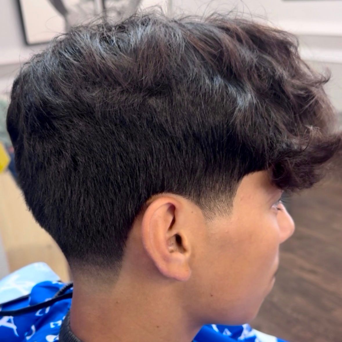 Side view of a person with a dark hairstyle, faded sides, and textured top.