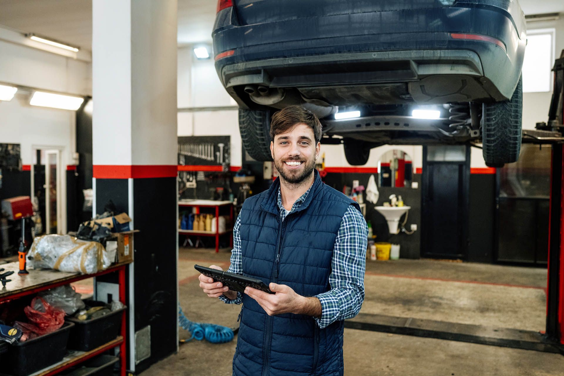Two men are looking at a tablet in a garage.