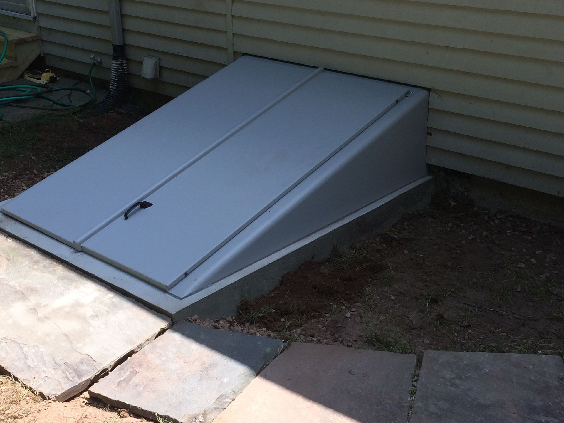 A gray door is sitting on the side of a house