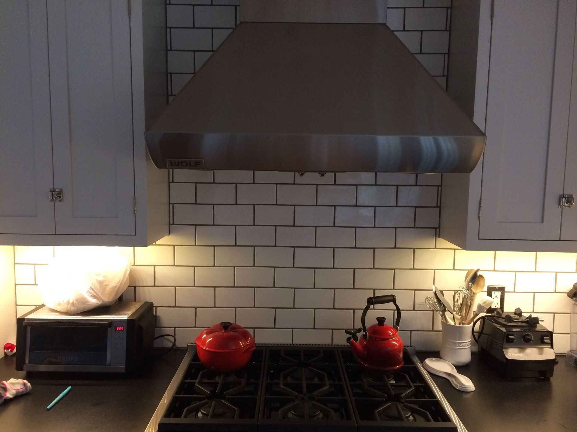 A kitchen with a stove top oven and a stainless steel hood
