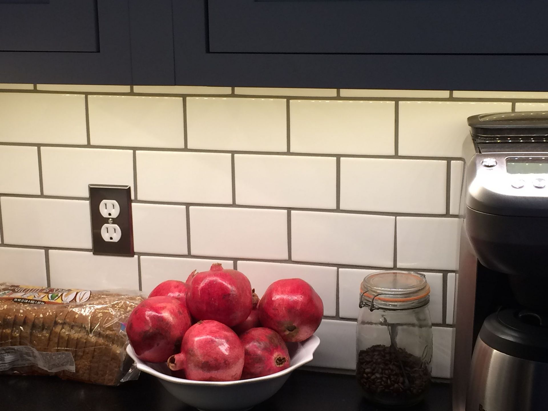 A bowl of pomegranates sits on a kitchen counter